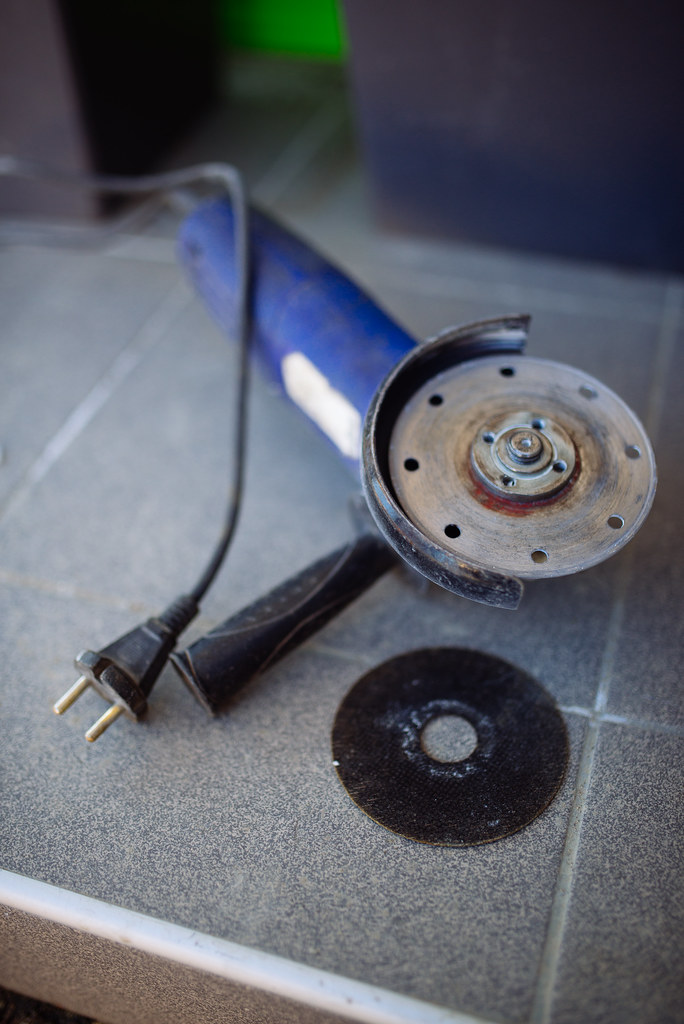 An angle grinding blade sits next to a blue, unplugged angle grinder.