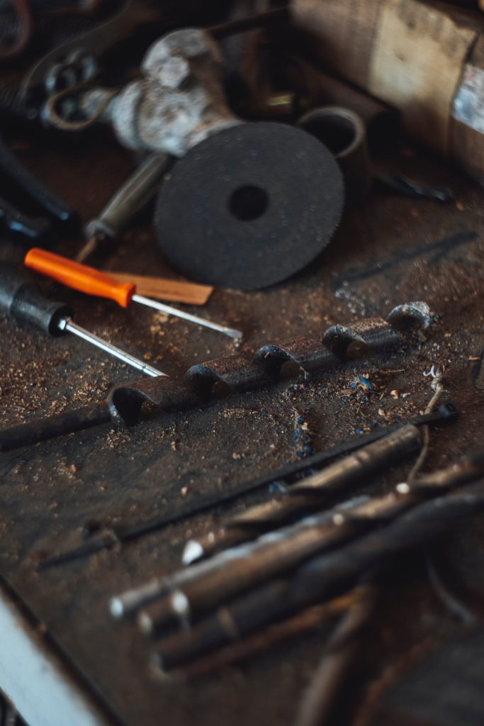 An angle grinder blade sits on a workbench next to screwdrivers and drill bits.