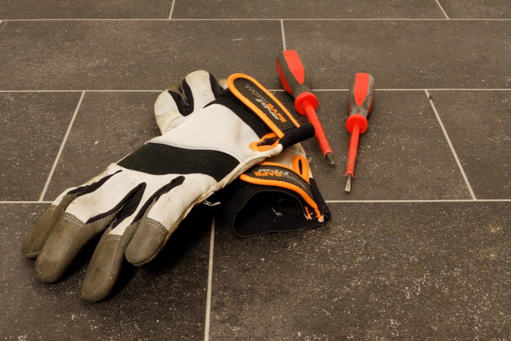 Orange and gray safety gloves lie next to red screwdrivers.