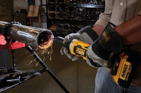 A man uses a DeWalt DCG426B 20V MAX Brushless 1-1/2" Cordless Die Grinder to grind a thick metal pipe.