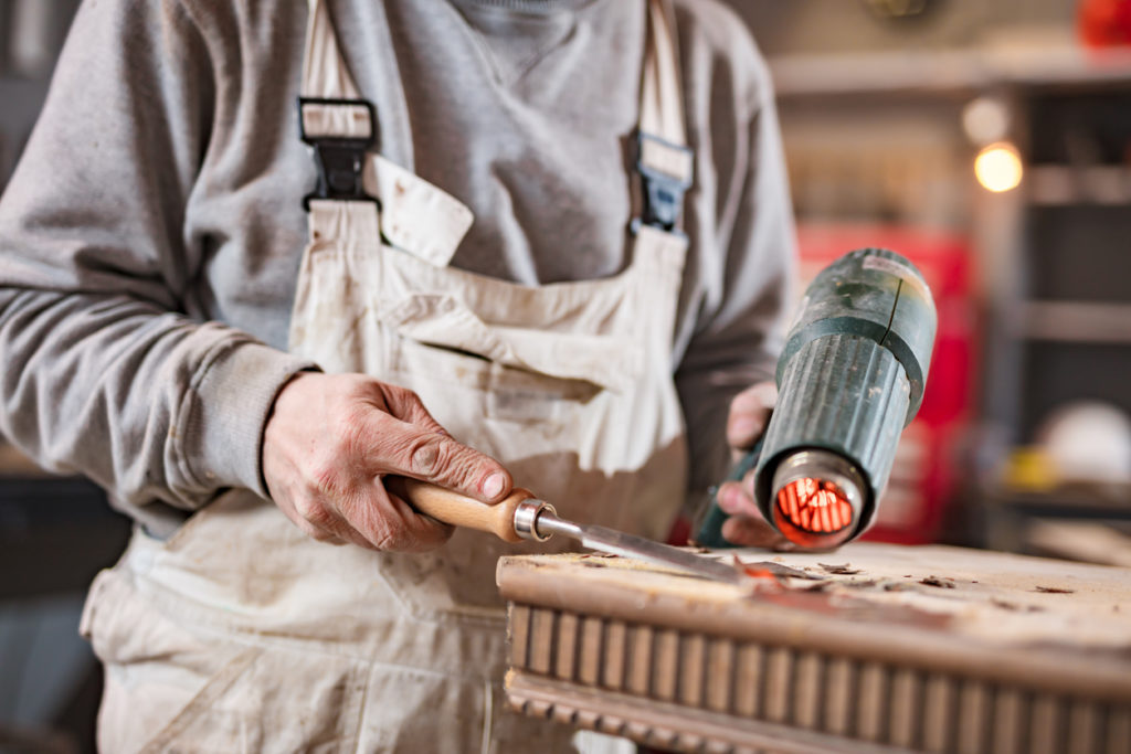 Male carpenter working on old wood in a retro vintage workshop.