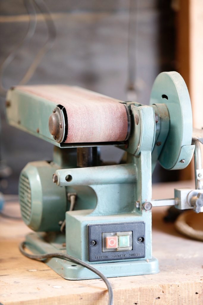 A green coded belt sander on a workbench