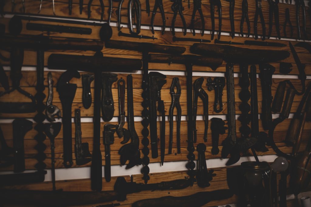 Hand tools organized neatly on wooden planks against a wall.