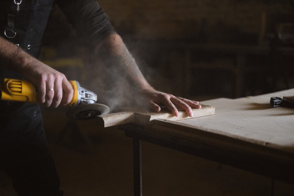 A craftsman using an angle grinder on a piece of wood.